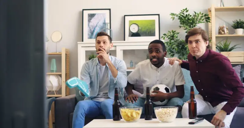 Friends watching a sports game on a couch during game day party