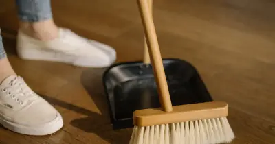 Asian woman cleaning a kitchen counter with a spray bottle and cloth, maintaining hygiene.