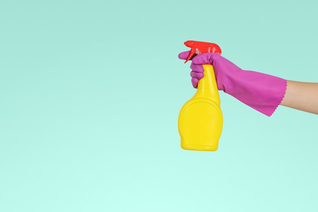 Gloved hand holding yellow spray bottle