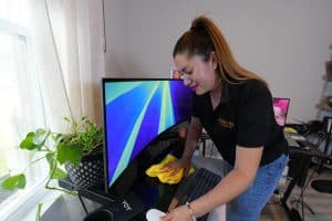 Residential Cleaning 8 A cleaning professional wipes down a computer monitor and keyboard.