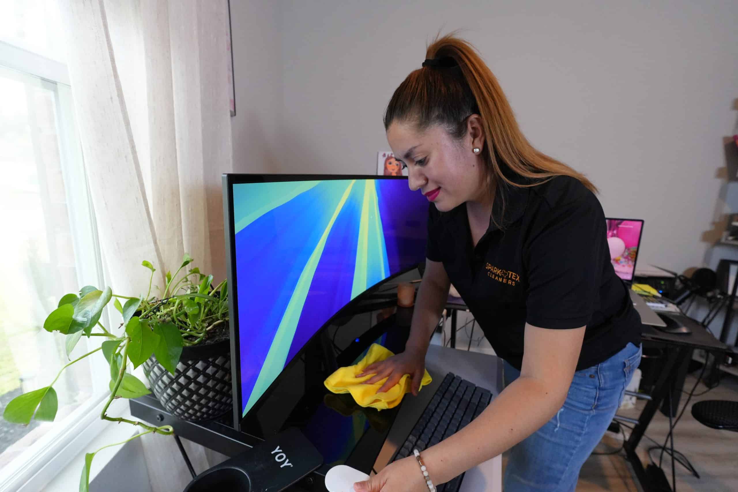 Residential Cleaning 16 A cleaning professional wipes down a computer monitor and keyboard.