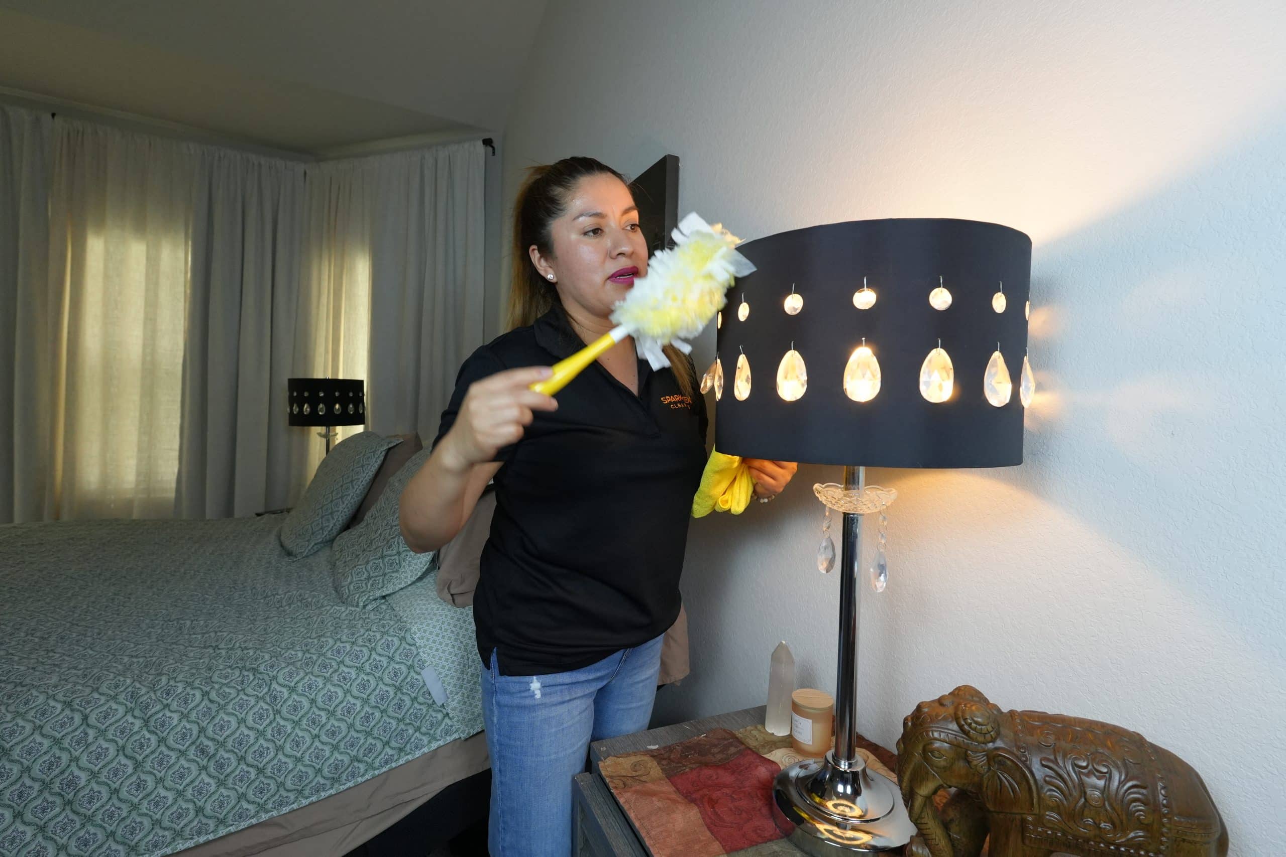 House cleaner in Conroe - dusting lampshade with feather duster