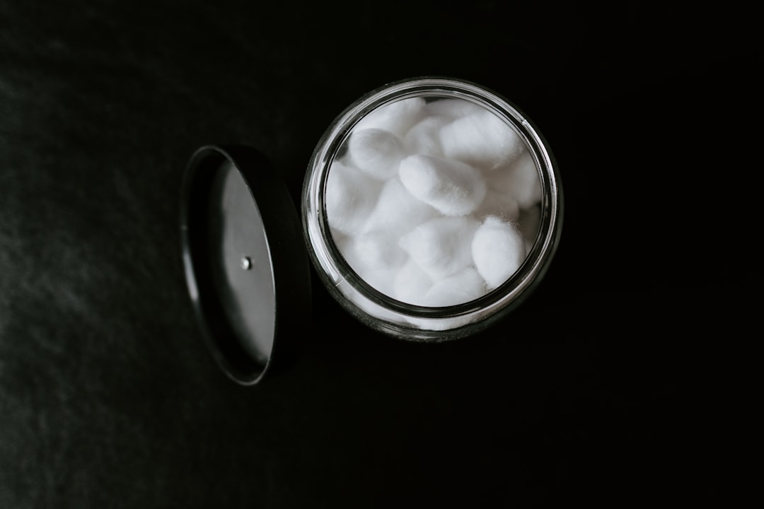 Jar of cotton balls on black background.