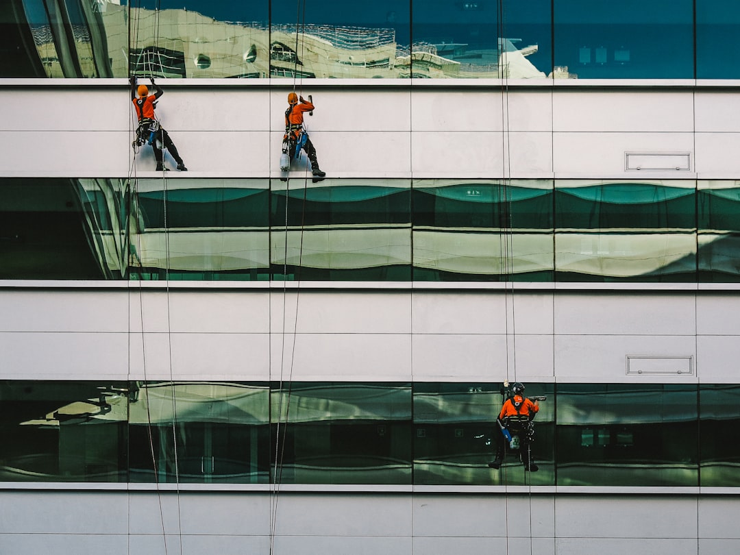 Workers cleaning windows on modern building facade.