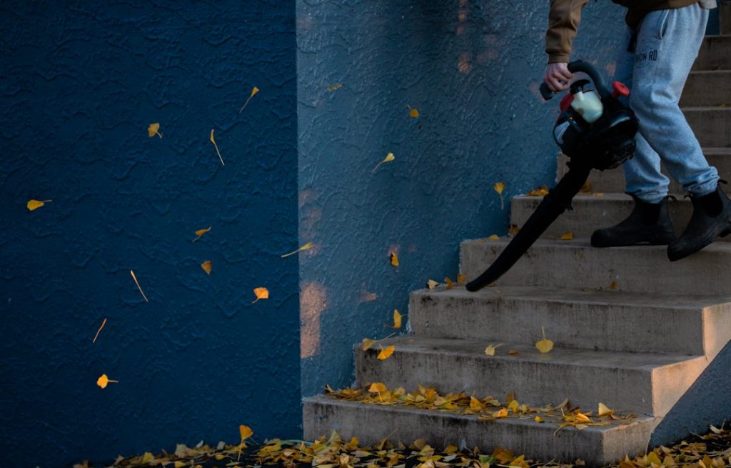 Person blowing leaves on outdoor stairs