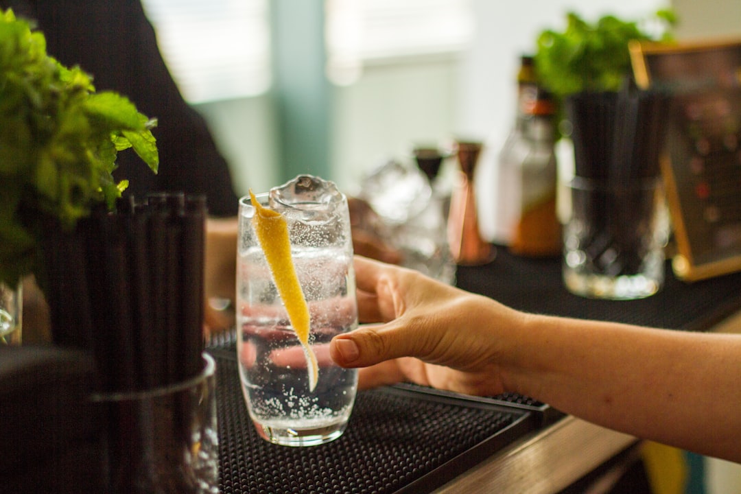 Hand holding cocktail with lemon twist at bar.