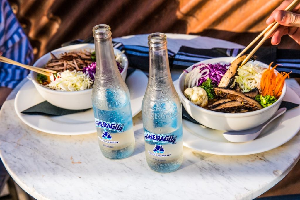 Bowls of ramen with sparkling water bottles.