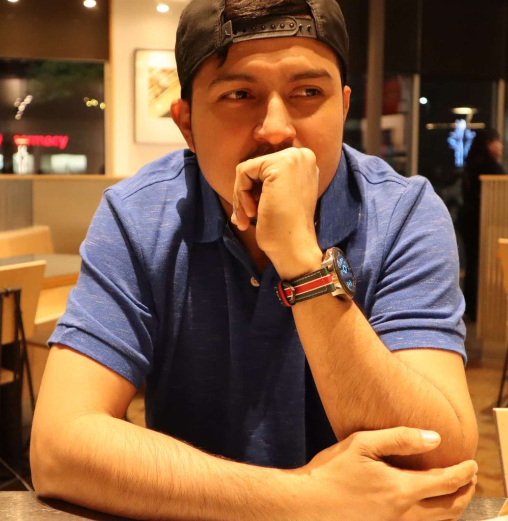 Thoughtful young man wearing a blue shirt and baseball cap, sitting at a table. Residential and Commercial Cleaning Services Cleaning in Conroe and Woodlands Texas