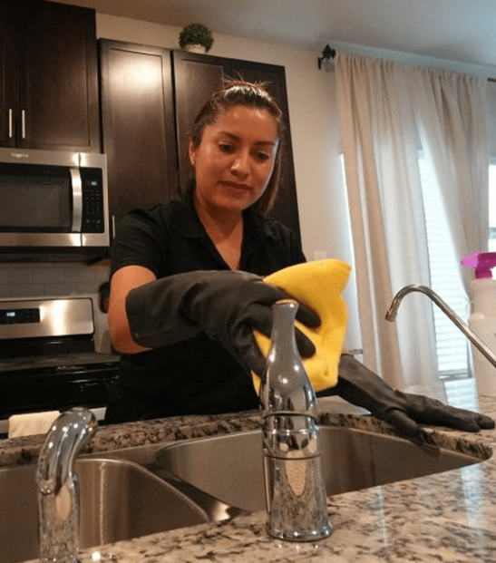Cleaning professional in Conroe/Woodlands, TX, wiping down a kitchen sink. Cleaning professional in Conroe/Woodlands, TX, wiping down a kitchen sink.